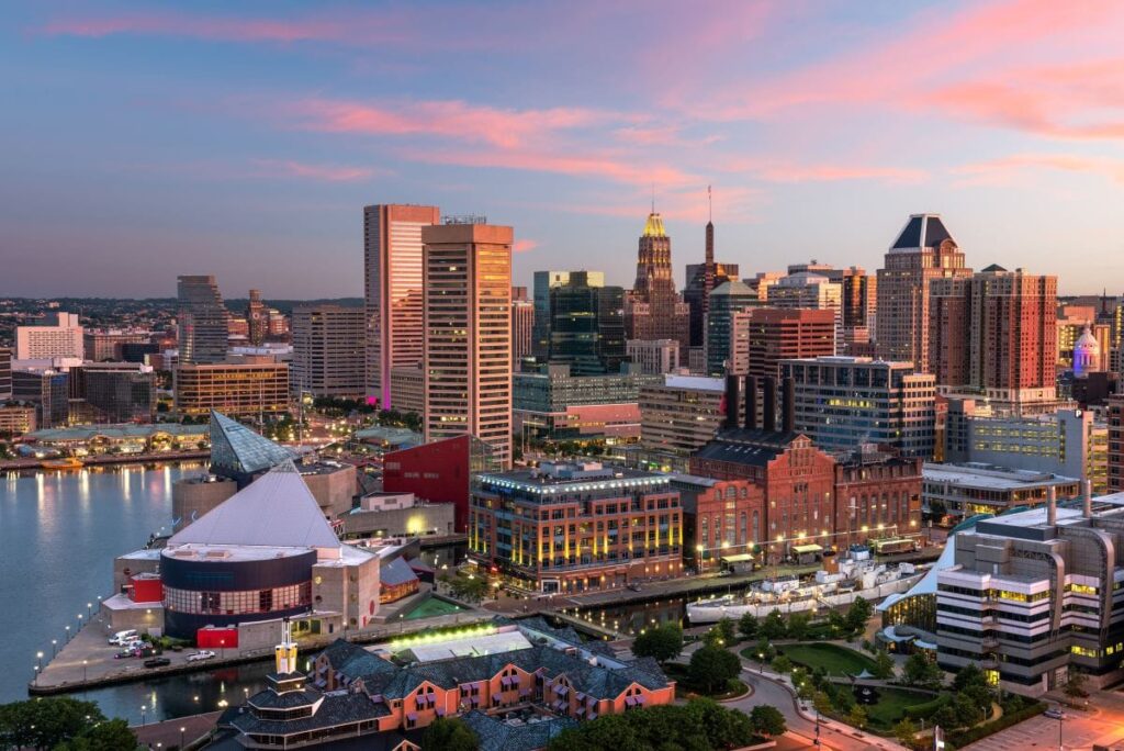 A vibrant city skyline at sunset with tall buildings, waterfront attractions, and colorful clouds reflecting in the calm harbor waters—an ideal backdrop for innovative businesses, including local drug testing services.