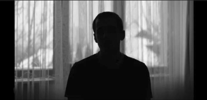 A person sits in front of a window with sheer curtains, their silhouette blurred by light. The scene evokes the privacy and confidentiality valued at Odosek Lab Solutions, specialists in DNA tests and drug screening.