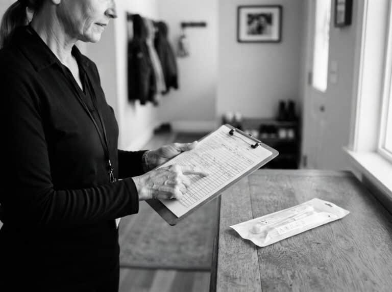 A mobile DNA test collector reviewing an appointment checklist beside a sealed sample collection kit.